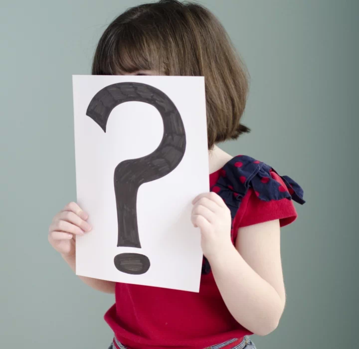 dziecko z kartką ze znakiem zapytania